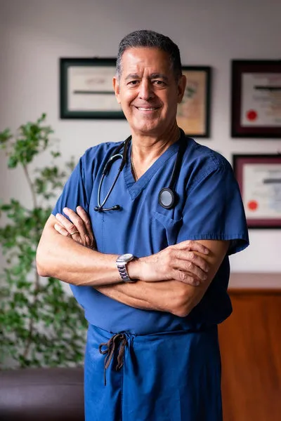 Smiling online doctor standing with folded arms, ready to provide telemedicine care
